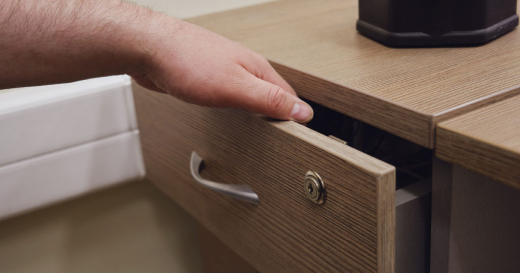 Man hand opens the office desk drawer, close up

