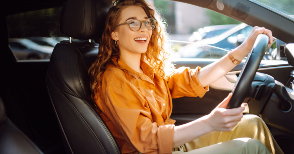 Smiling woman driving a car. Young traveler driving. Car travel, lifestyle concept.