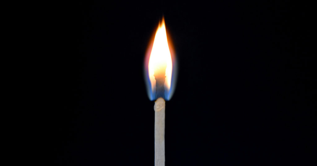 a matchstick that is burning and in flame in a dark room