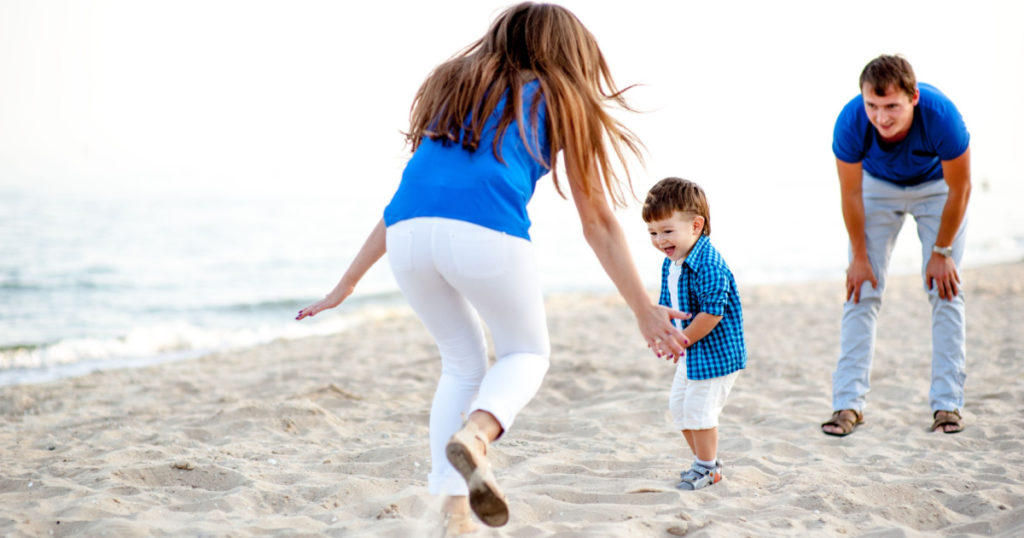 Man woman and child run on the beach near the ocean and feel happy