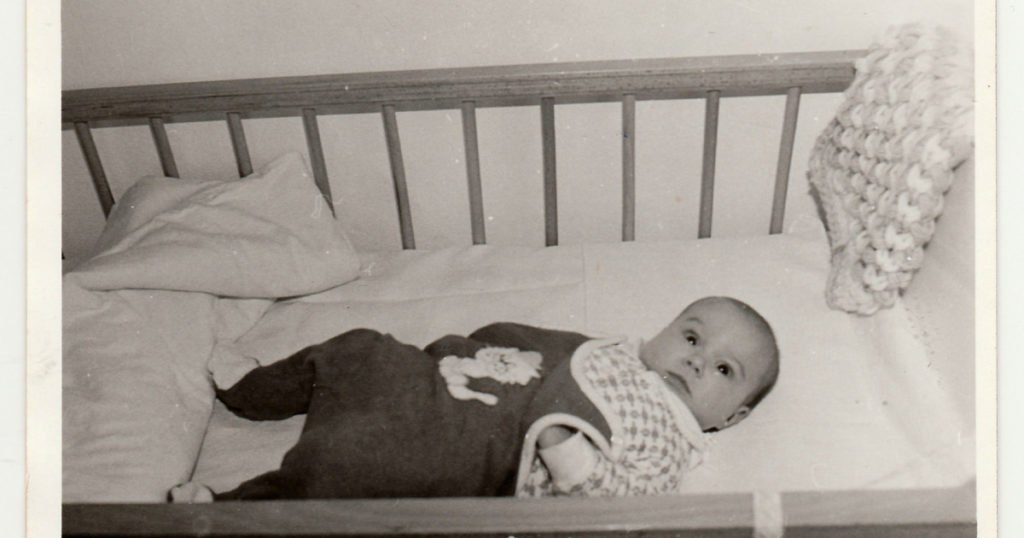 THE CZECHOSLOVAK SOCIALIST REPUBLIC - CIRCA 1970s: Retro photo shows cute baby who lies in a bed. Cute baby lies in the crib. Adorable toddler in his cot. Black and white vintage