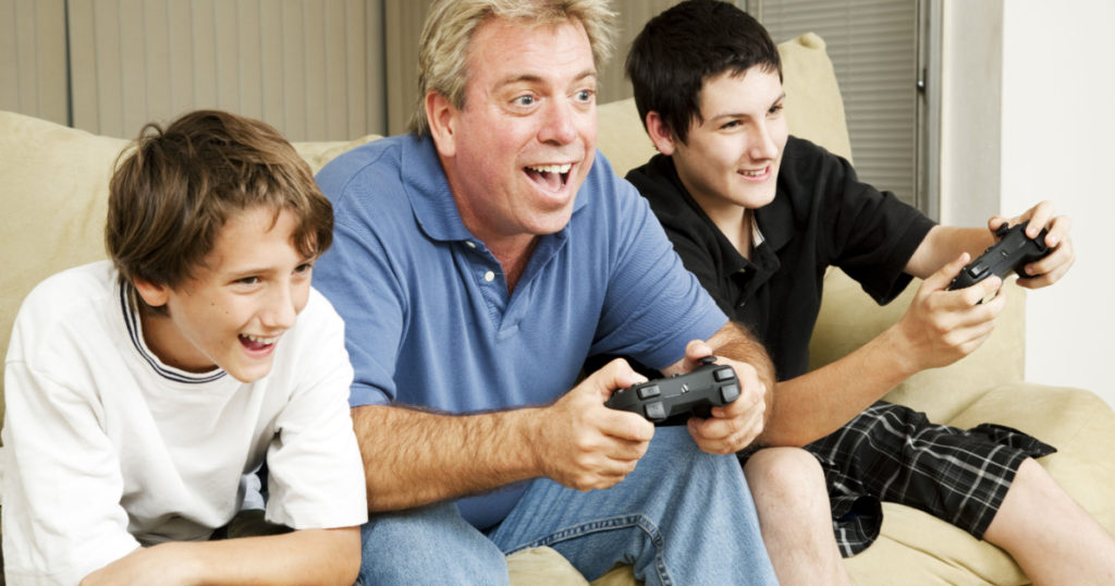 Uncle plays video games with his nephews. Could also be father.