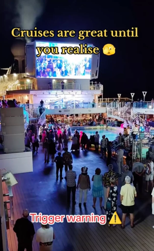 Cruise deck with people watching a big screen next to a pool.