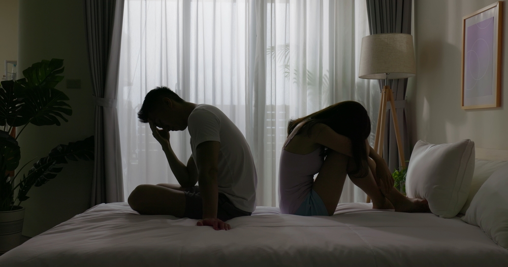 marriage problem relationship difficulties concept - asian young couple sitting separately on bed are sad after having argument and angry conflict