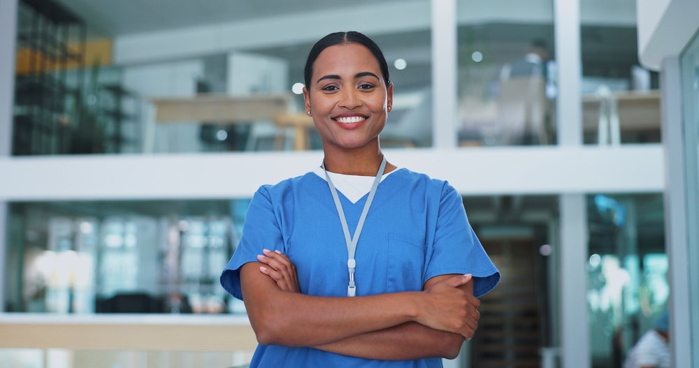 Nurse, woman and arms crossed with portrait, smile and pride for career in healthcare at hospital. Doctor, medical worker or person with confidence for wellness in clinic lobby with trust and support