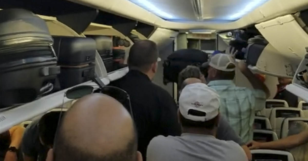 passengers standing in aisle of plane after landing