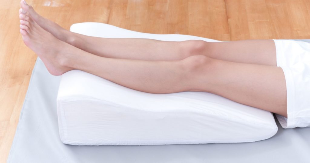 A woman's legs lay down on a pillow for relaxing and preventing varicose vein