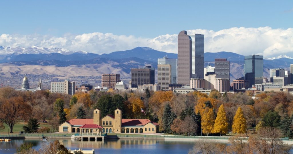 Scenic of Denver Colorado skyline, with Rocky Mountains in the background and City Park Lake in the foreground.