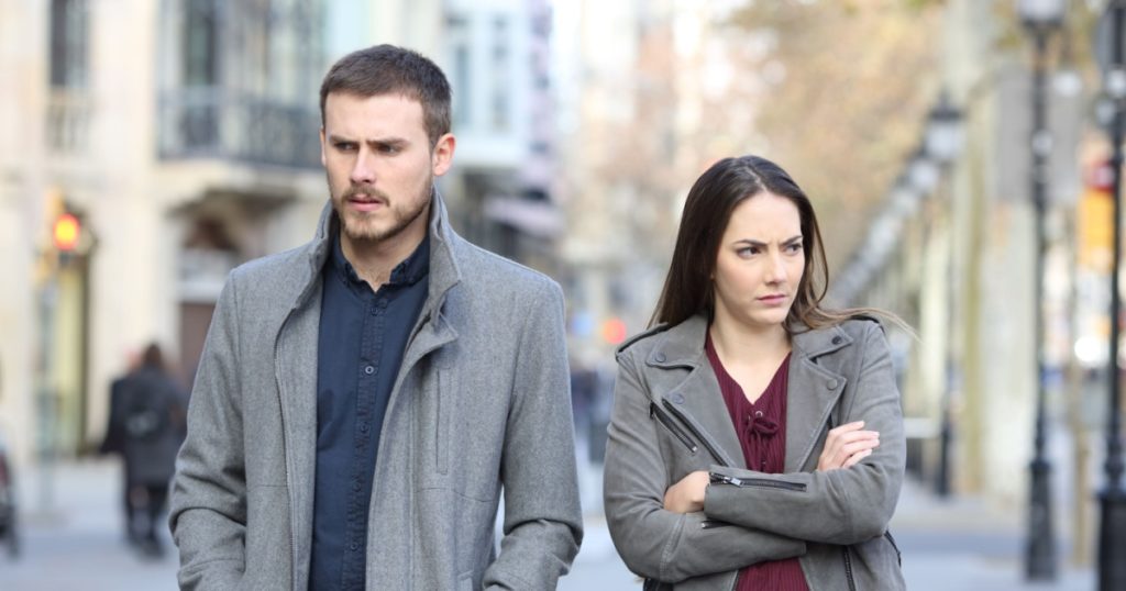 Front view portrait of an angry couple walking in the street after argument