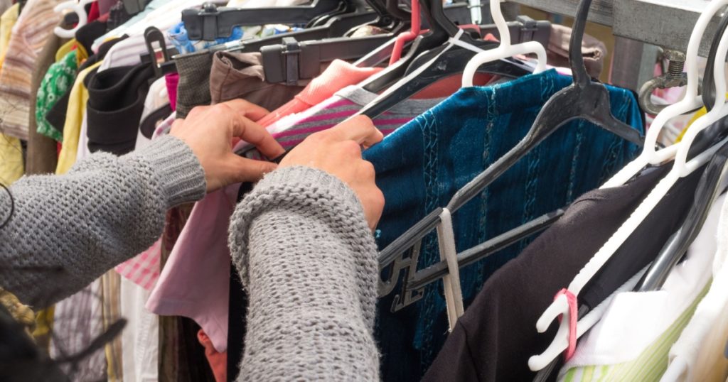 Female hands rummaging in clothes in a second hand shop
