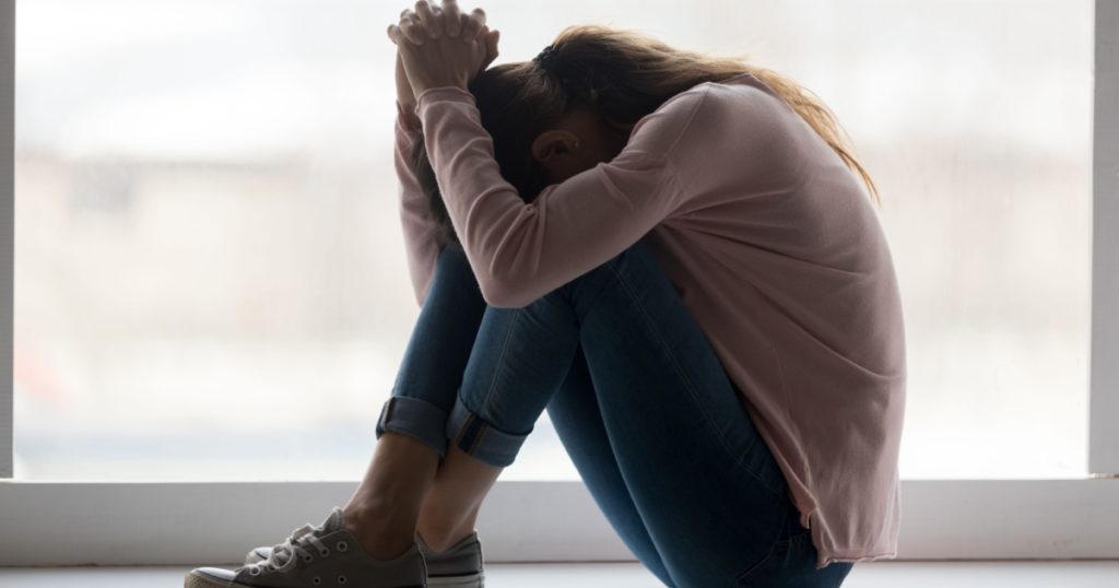 Depressed sad teen girl sit on sill crying alone at home, upset desperate young woman feeling frustrated anxious regret mistake suffer from unwanted teenage pregnancy abortion problem concept
