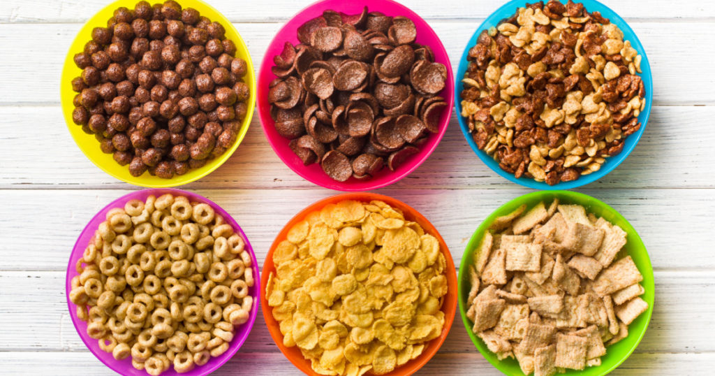 top view of various kids cereals in colorful bowls on wooden table