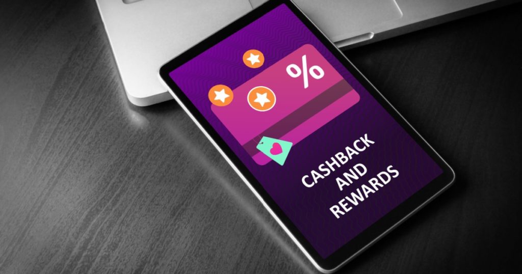 Cashback and Rewards - loyalty program and retail customer money refund service concept. Tablet PC lying on a wooden table with cashback discount card and rewarding marketing points on the screen