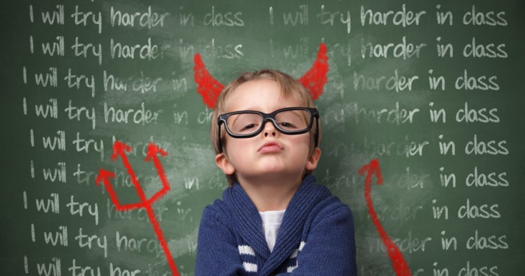 Naughty devil schoolboy with lines written on a blackboard reading I will try harder in class and devils horns, tail and pitchfork. Detention and school discipline / punishment concept