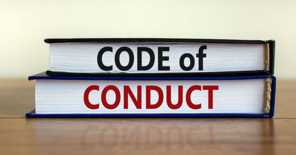 Code of conduct symbol. Concept words 'Code of conduct' on books on a beautiful wooden table, white background. Business and code of conduct concept. Copy space.