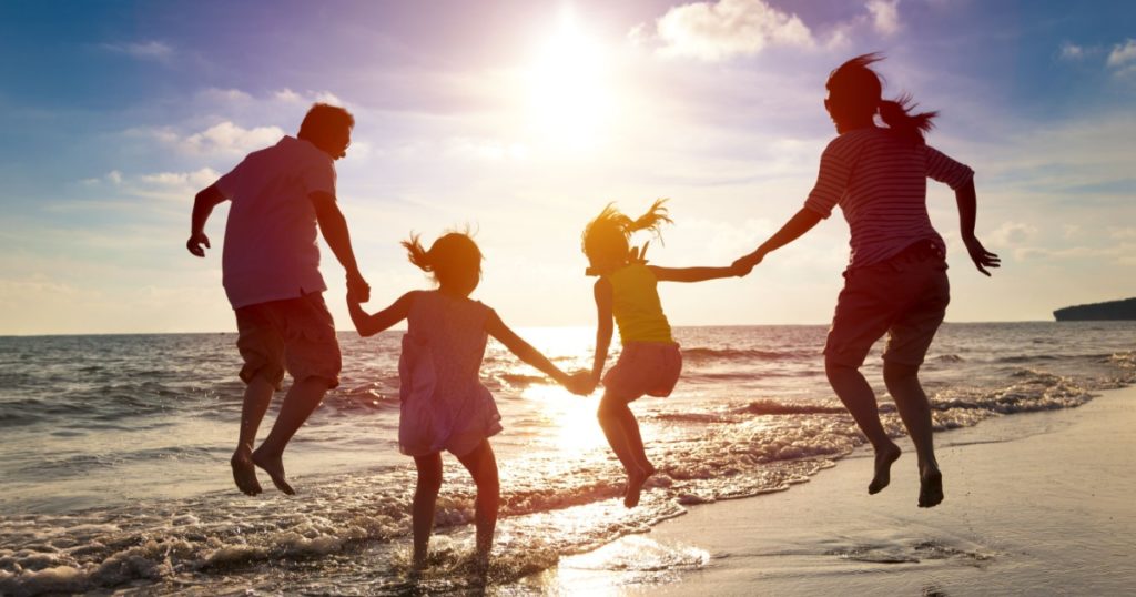 happy family jumping together on the beach