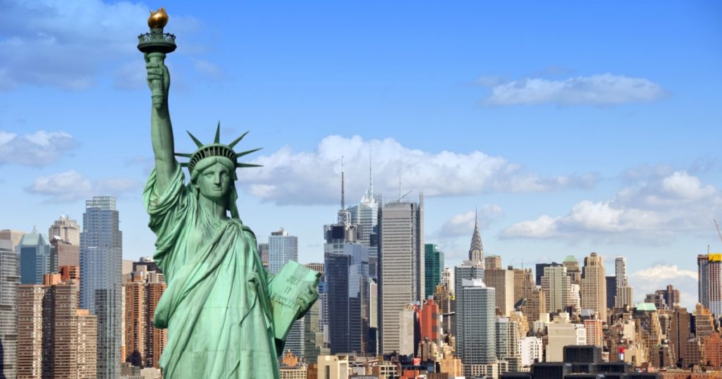 new york city skyline cityscape with statue of liberty over hudson river. with midtown Manhattan skyscrapers and freight sailing ship in usa america.