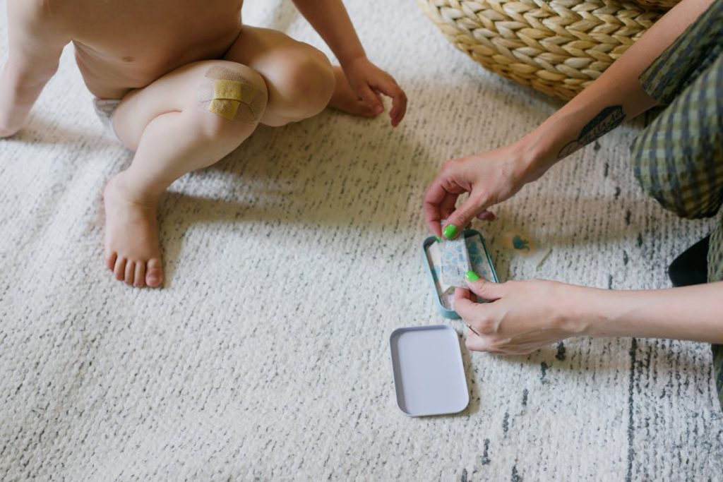 Crop unrecognizable mother with kid choosing adhesive plaster on floor
