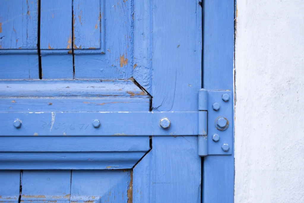 Shabby blue wooden door with metal hinge
