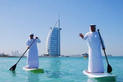 Paddleboarding in traditional thobe and headdress epitomizes Dubai's unique fusion of ancient customs and modern trends.