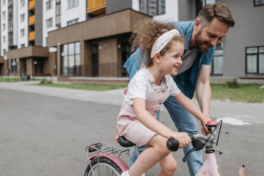 Father teaching daughter how to ride bicycle