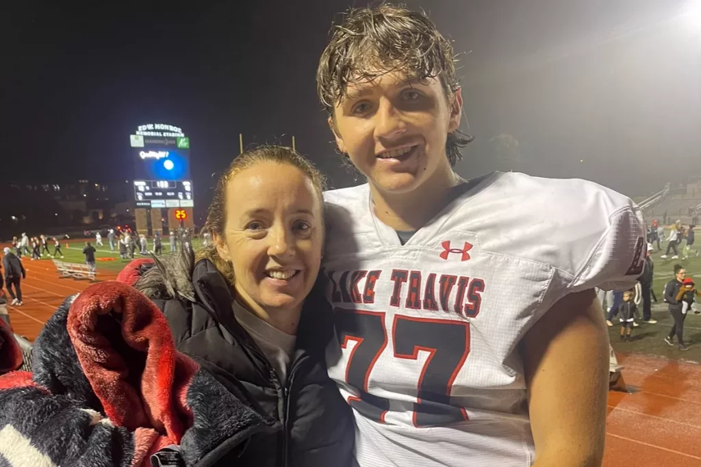 Mom and son standing together at football game. 