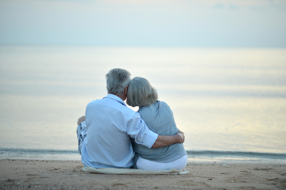 Portrait of happy elderly couple resting on tropical beach