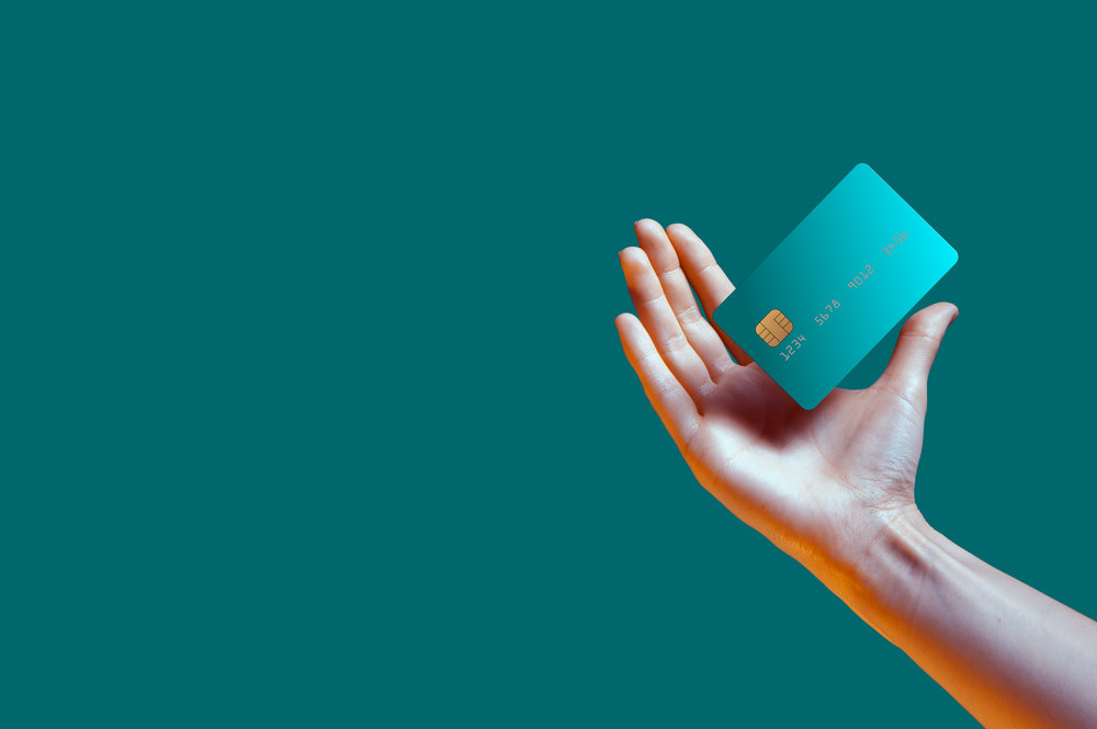 Close up female hand holds levitating template mockup Bank credit card with online service isolated on green background