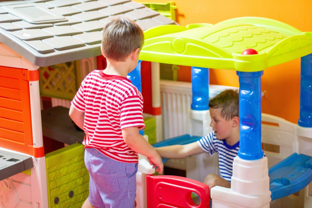 Children play in indoor playground. Two boys playing with colored toy houses. Indoor play areas for Children’s Early Development concept
