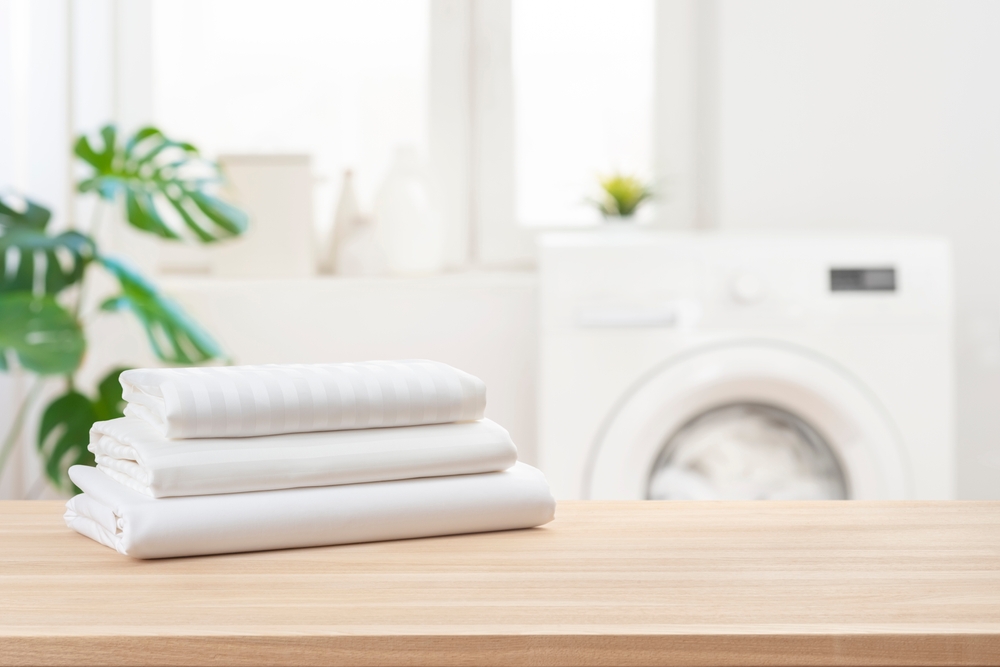 Stack of clean laundry bedding sheets on table in bathroom