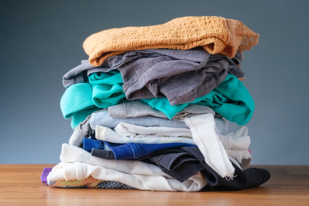 A pile of outgrown clothes of a child on the table, too small for growing up age, preparing to laundry, and donation