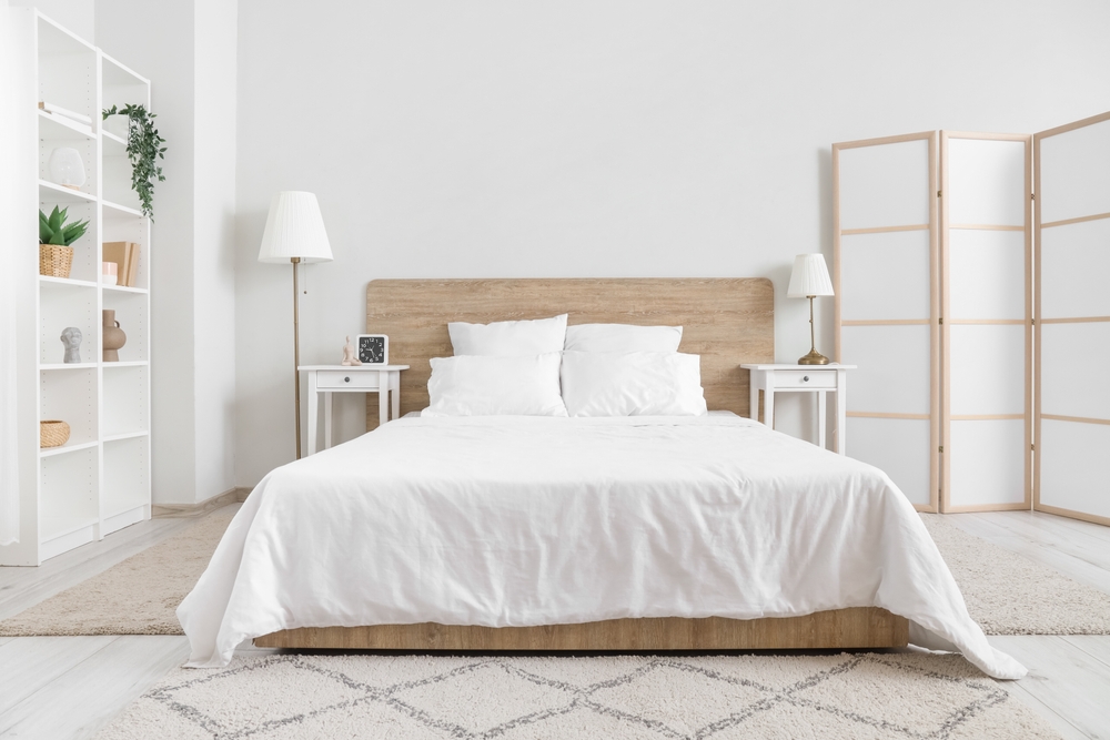 Interior of bedroom with bed, shelving unit and folding screen