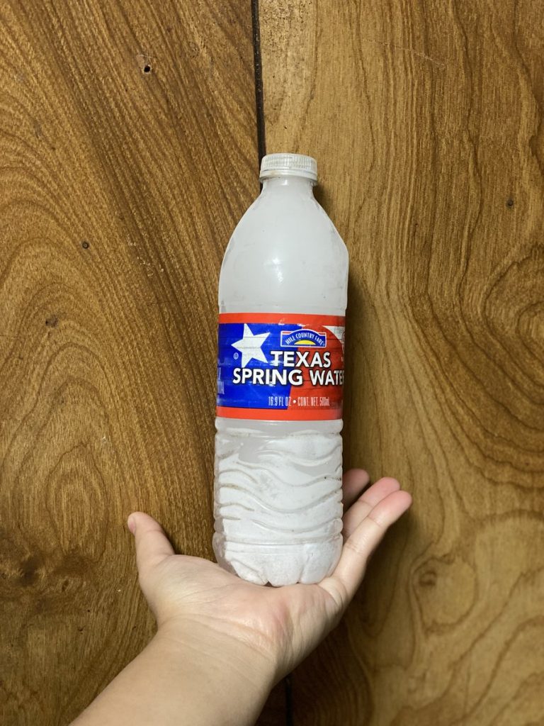 hand holding frozen water bottle 
