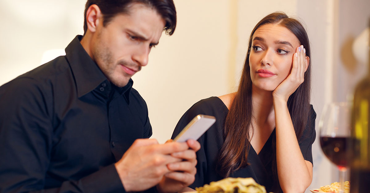 male and female couple. Man is ignoring his partner while using his phone.