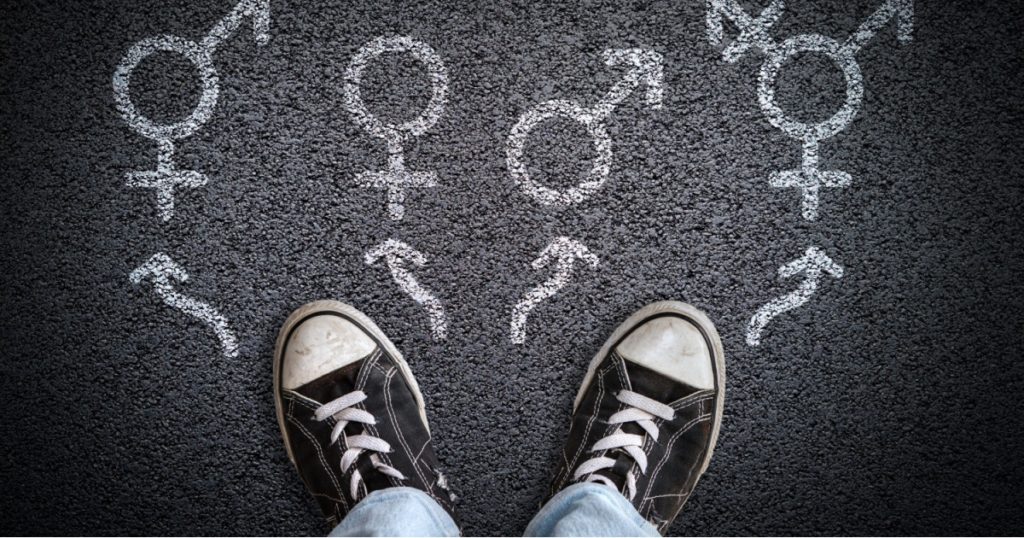 A person standing on asphalt road with gender symbols of male, female, bigender and transgender. Concept of choice or gender confusion or dysphoria.