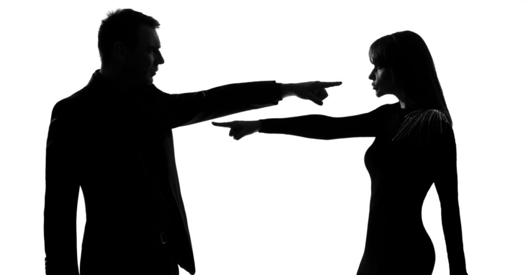 one caucasian couple man and woman pointing at each other expressing accusation in studio silhouette isolated on white background