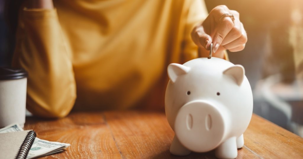 woman hand putting money coin into piggy for saving money wealth and financial concept.