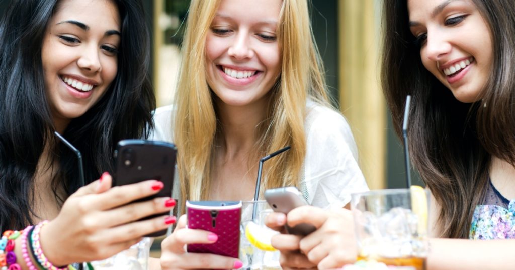 three girls chatting with their smartphones