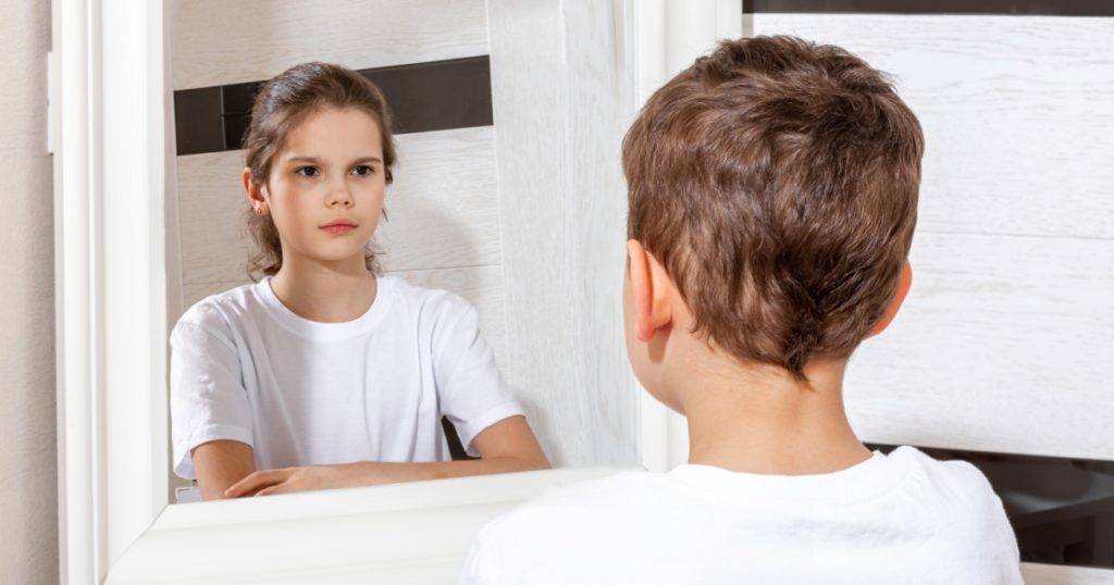 Reflection of a boy in the mirror by a girl. Sister and brother concept. Boy and girl. Concept of Gender dysphoria.
