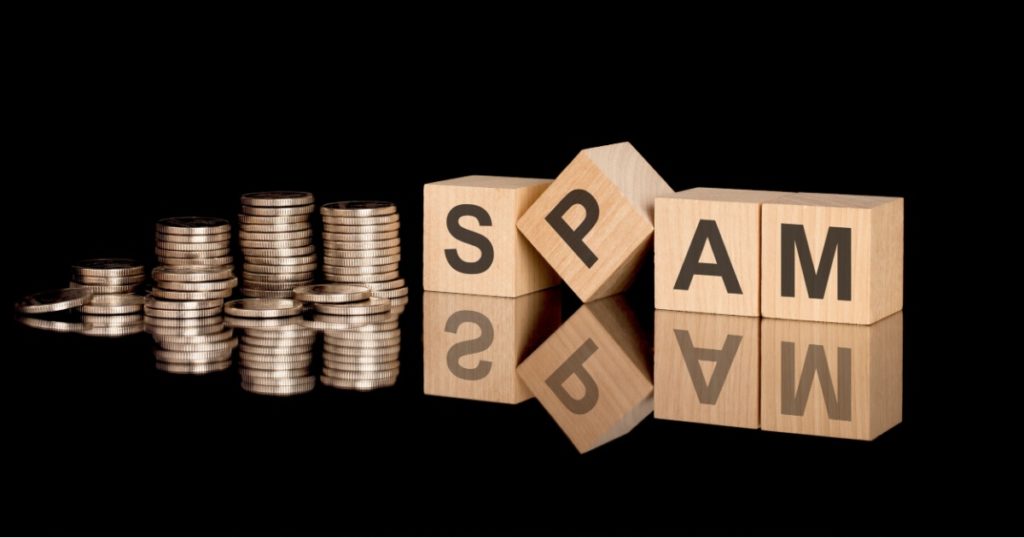 Spam. wooden cubes. black background. stacks with coins. inscription on the cubes is reflected from the surface of the table. business concept.