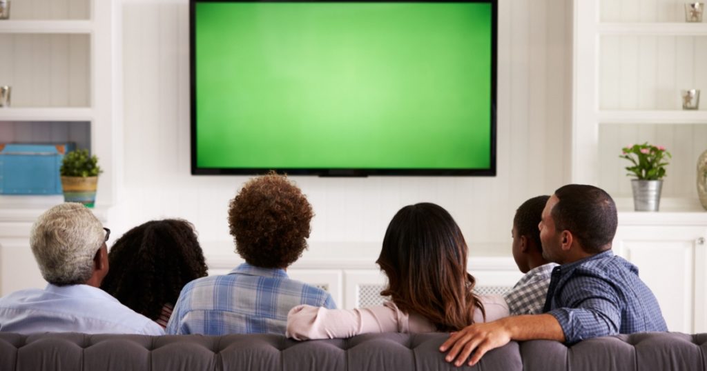 Multi generation family watching TV at home, back view