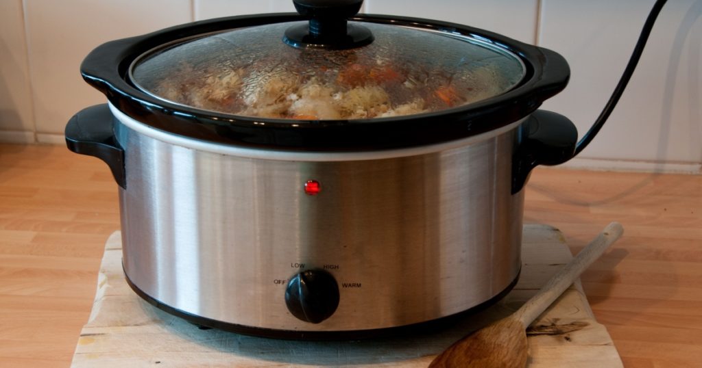 Slow cooker with wooden spoon on chopping board cheep winter cooking