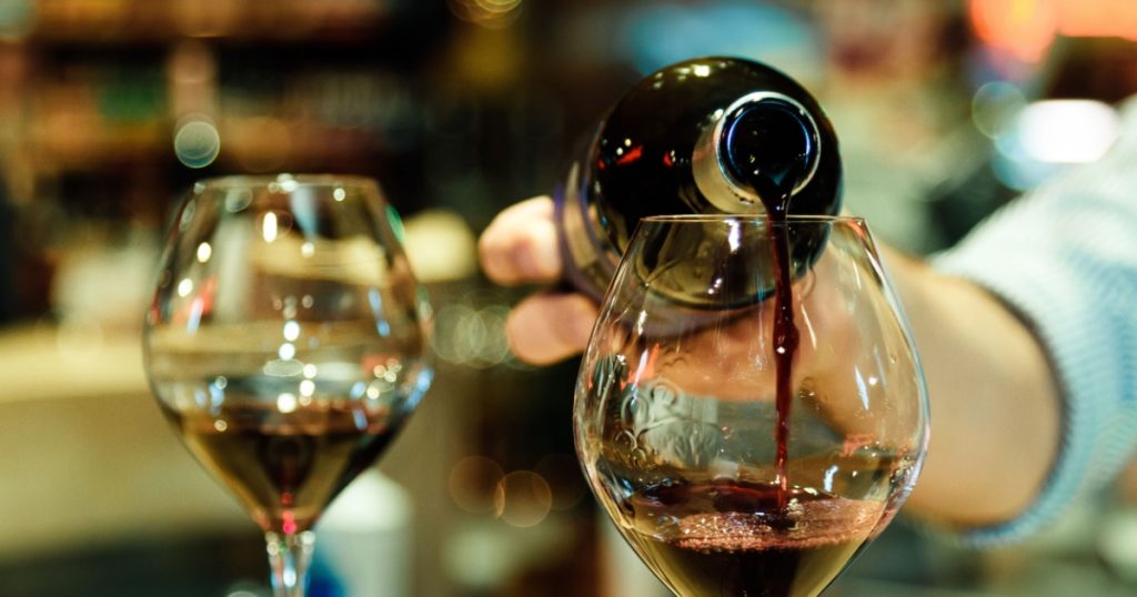 Red wine pouring into a wine glass. Shallow depth of field.