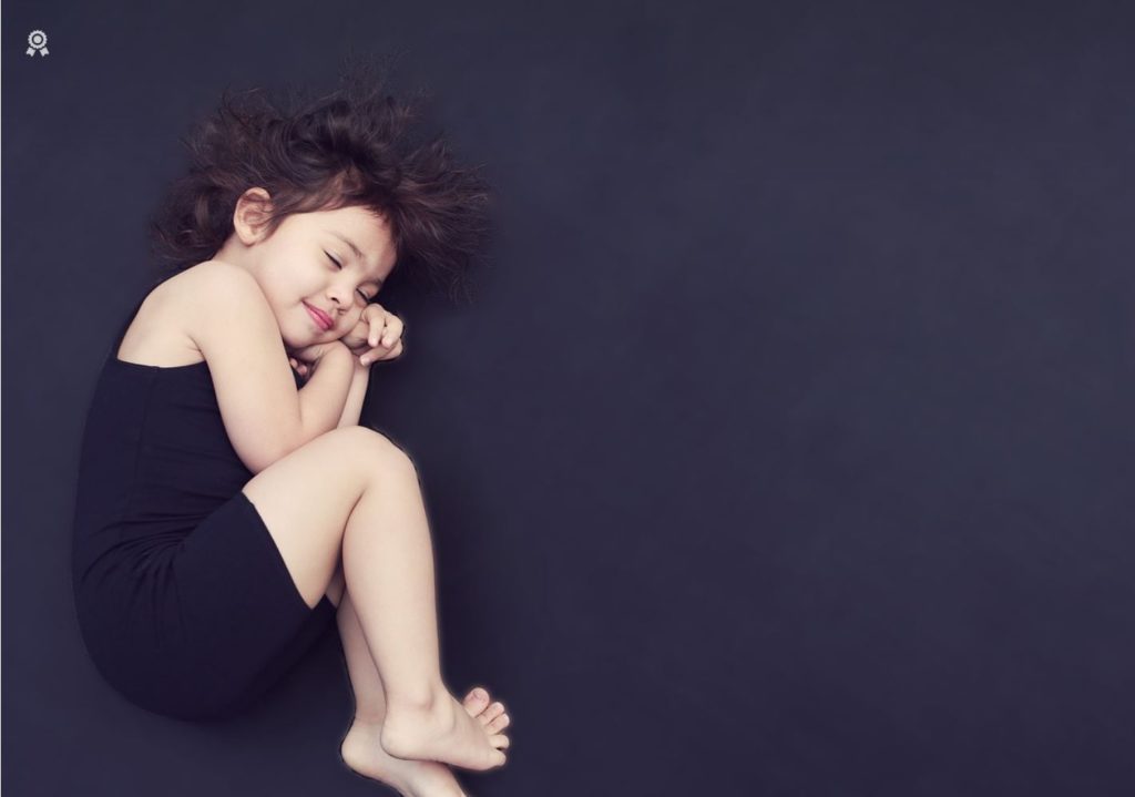 Girl curled up on the floor. Black background.