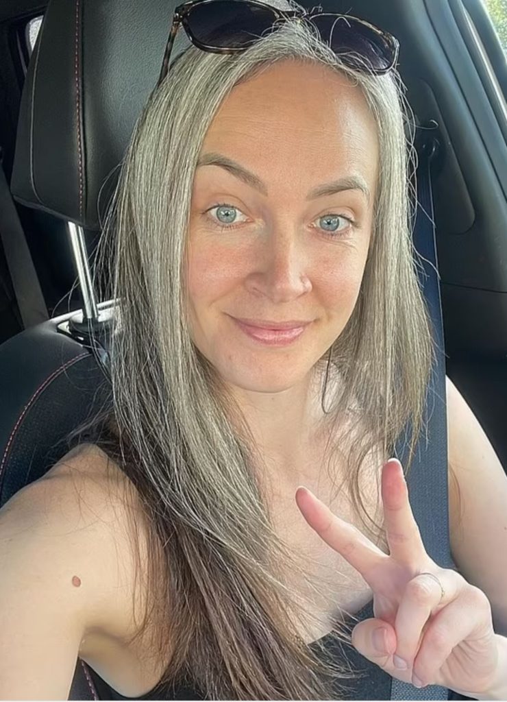 Aging woman in car, smiling and wearing no makeup.