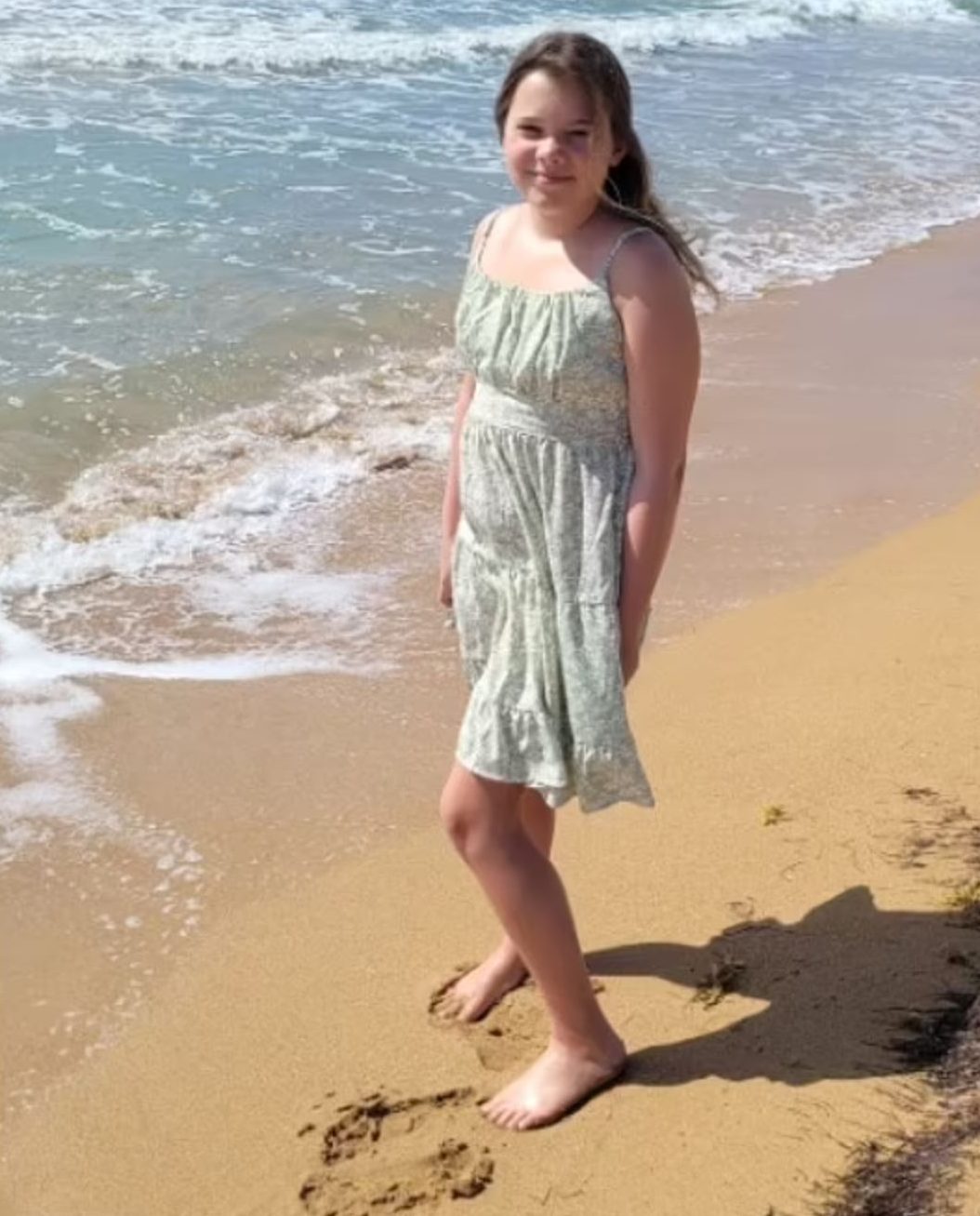 Girl standing on a beach. Ocean and sand in the background. 