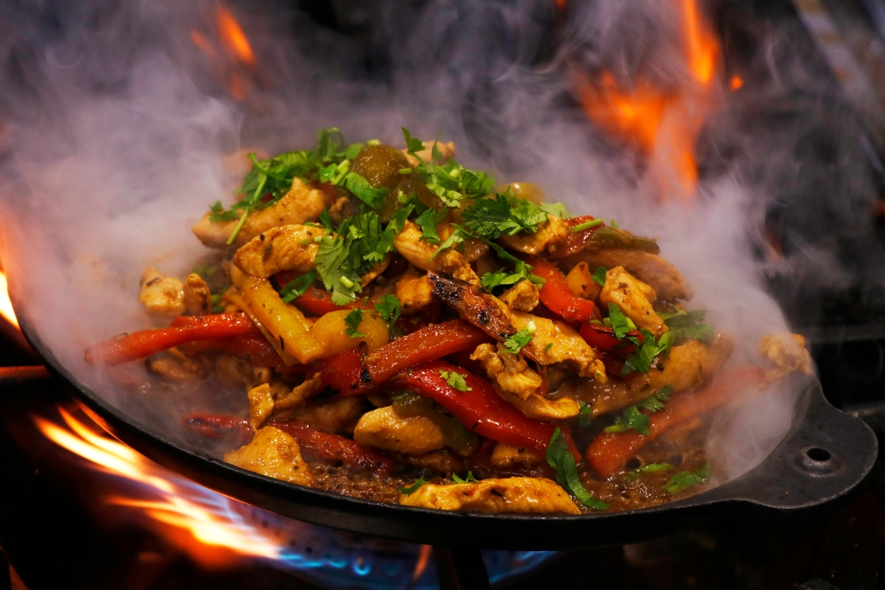 mexican food, chicken fajitas served on a hot smoking sizzling plate