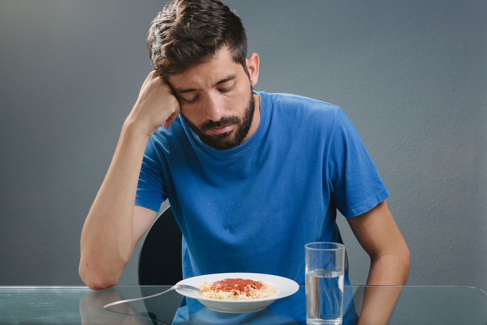 Portrait of man with no appetite in front of the meal. Concept of loss of appetite