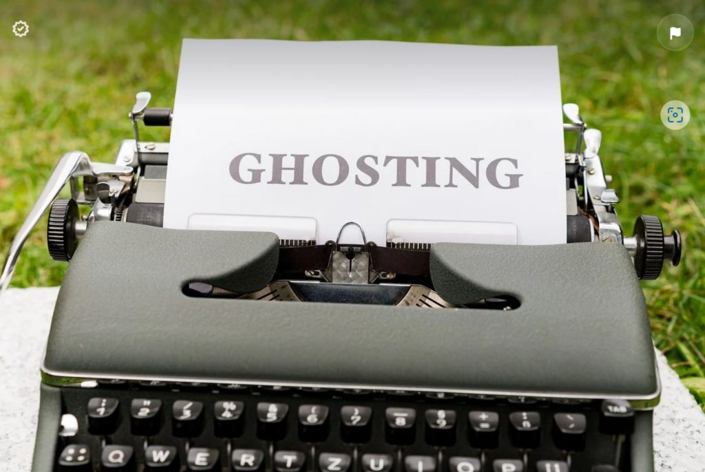 A typewriter that says ghosting, with grass in the background