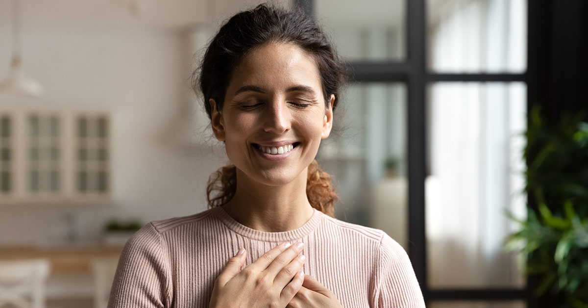 happy woman smiling with hands placed on chest